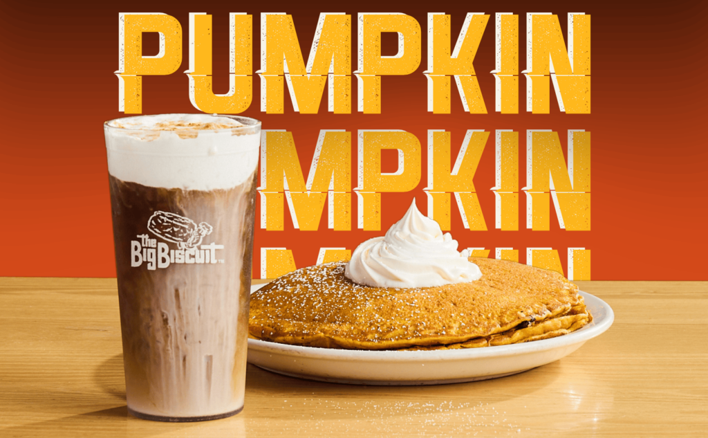 Cup of Pumpkin Cream Cold Brew next to stack of Pumpkin Pancakes sitting on table with "PUMPKIN" words in background